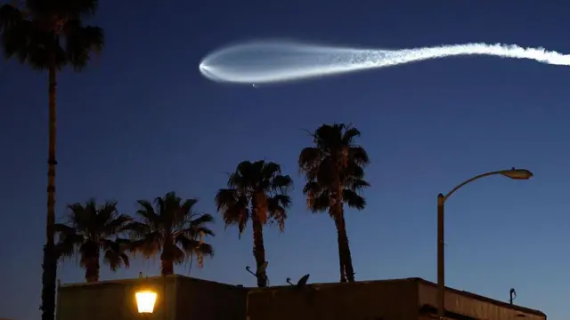 Una estela blanca dejada en el cielo oscuro por un cohete que lleva uno de los satélitles de Starlink.