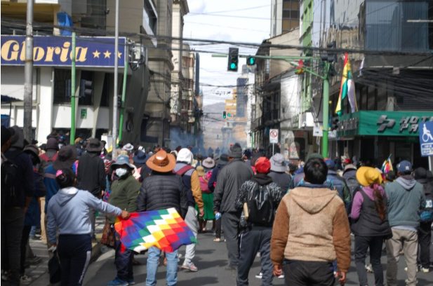 Los manifestantes esperan para unirse al frente mientras se acumulan gases lacrimógenos cerca de la Asamblea Plurinacional. Crédito de la imagen: Joseph Bouchard