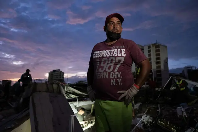 Un hombre, al atardecer, rodeado de edificios destruidos por los terremotos. 
